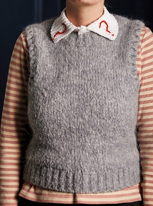 A knitted vest with a crochet collar with a question mark