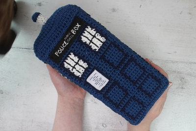 A crochet tardis being held up