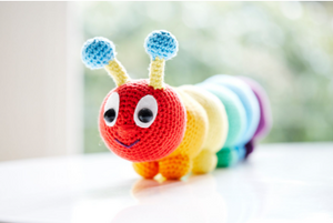 A colourful crochet caterpillar on a table