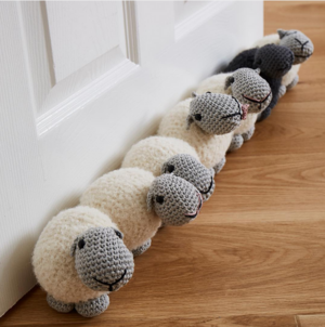 A draft excluder made from crochet sheep at the bottom of a door