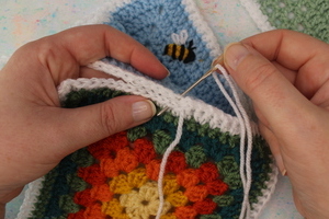 A close up of knitted squares being joined together